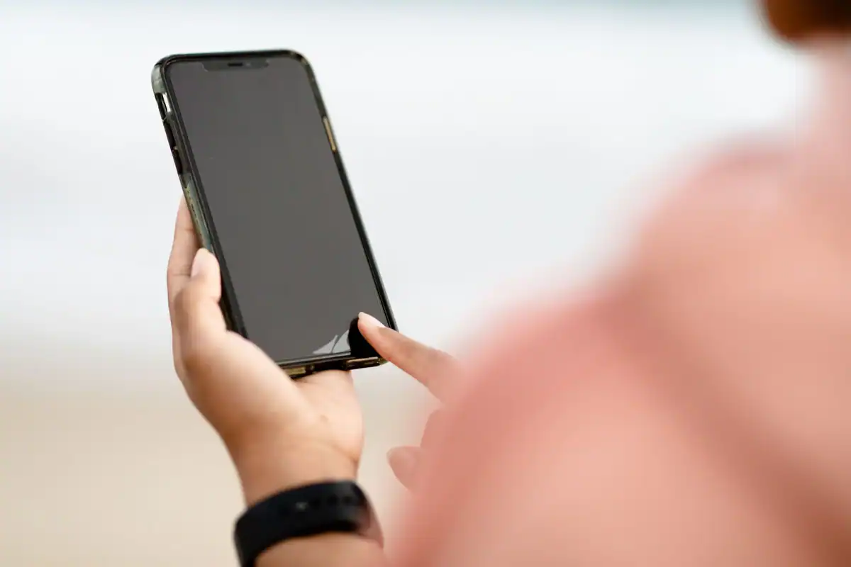 Mână care ține un telefon negru pentru a verifica actualizările de sistem