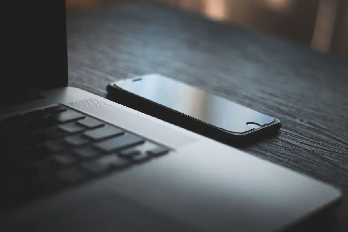 Telefon așezat lângă tastatura unui laptop, pregătit pentru actualizarea sistemului