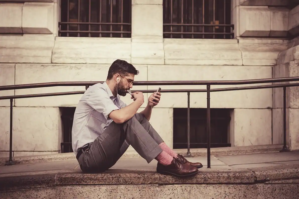 Bărbat așezat pe o treaptă care folosește telefonul, pe gânduri înainte de alegerea sistemului
