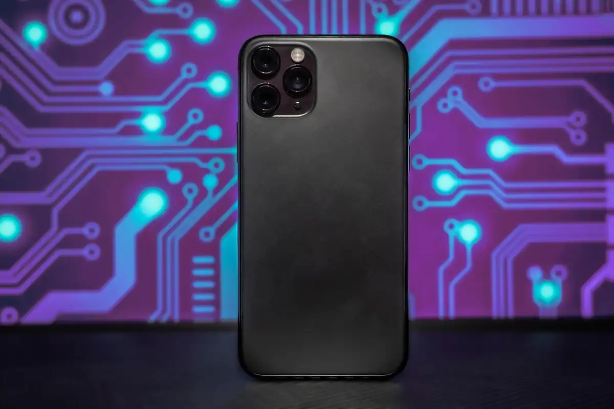 Spatele unui telefon negru cu trei obiective, pe un fundal cu circuite violete