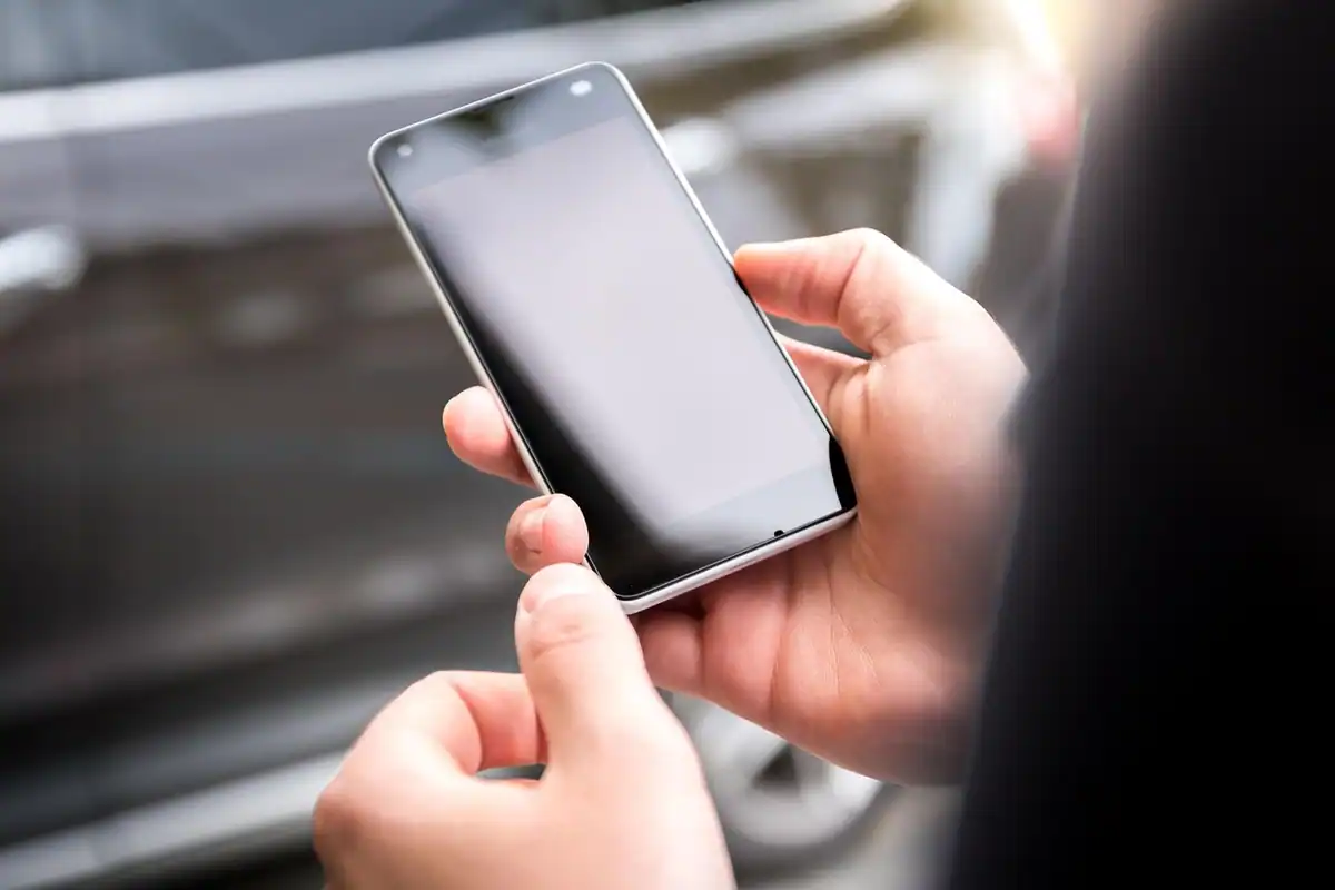 Mâini care țin un telefon cu ecranul stins, la începutul configurării inițiale