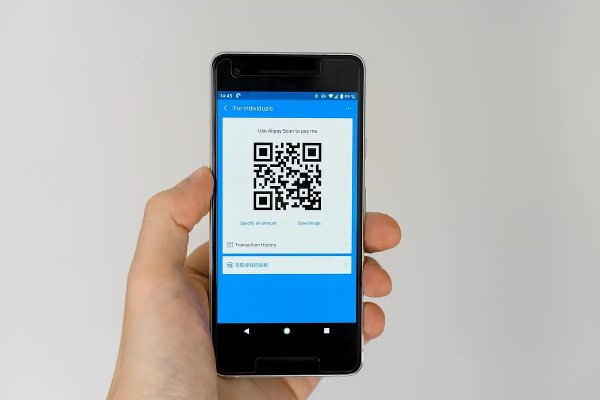 Mână care ține un telefon cu un cod QR pe ecran pentru activarea eSIM