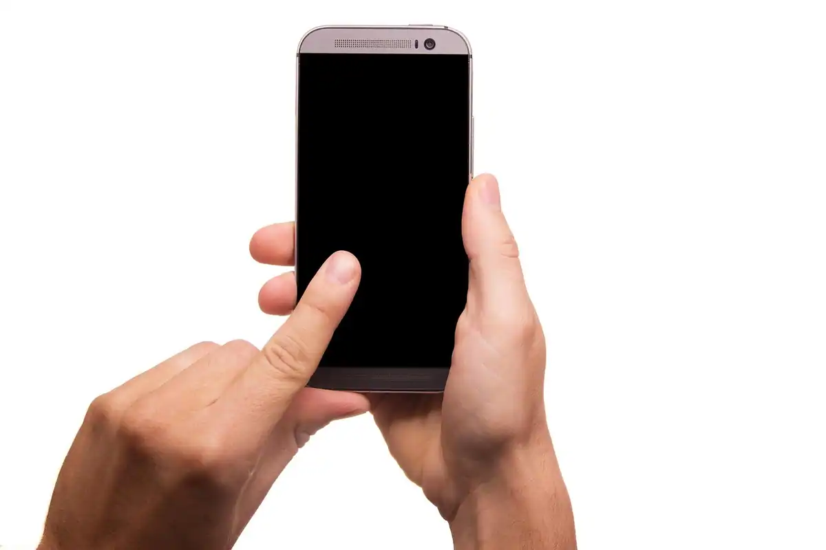 Două mâini care țin un telefon și ating ecranul tactil