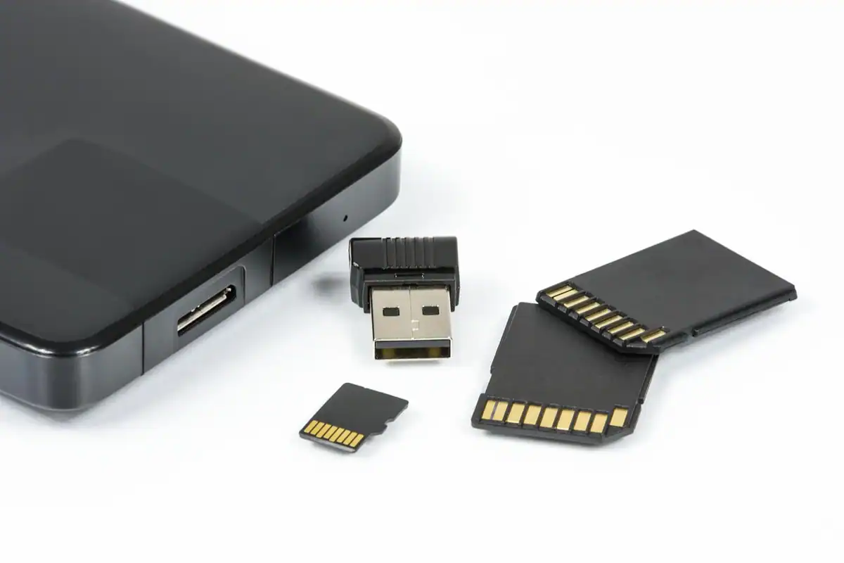 Carduri de memorie și un stick USB lângă un hard disk extern