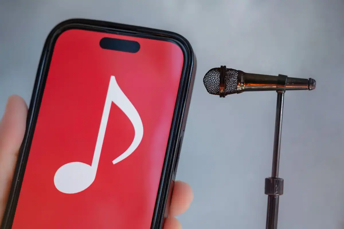Telefon cu o pictogramă muzicală mare pe ecranul roșu, lângă un microfon