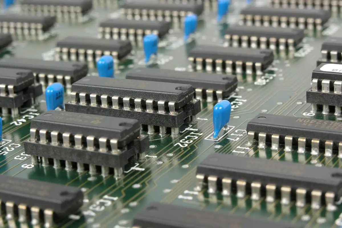 Plăcuță electronică cu multe cipuri negre și condensatoare albastre