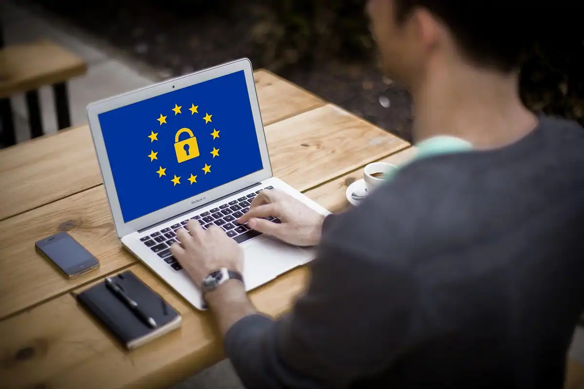 Bărbat la un laptop cu un lacăt și stele europene pe ecran
