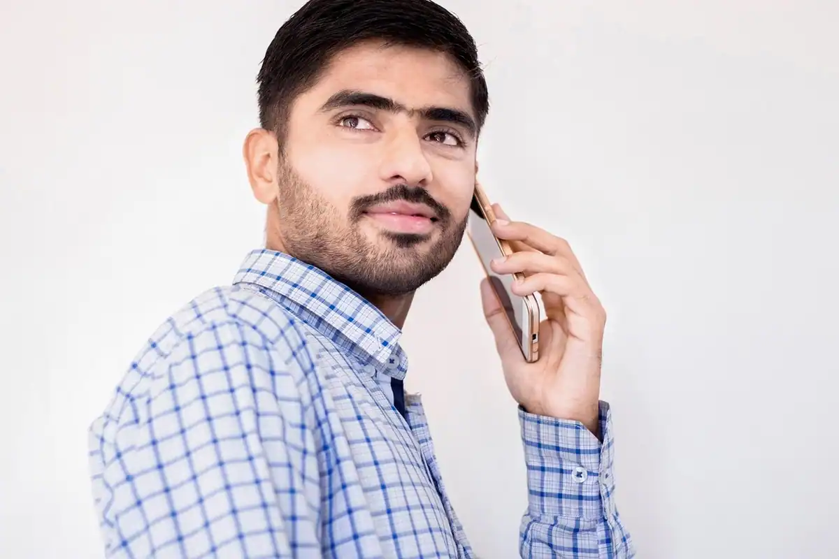 Bărbat într-o cămașă în carouri, vorbind la telefon cu privirea în sus
