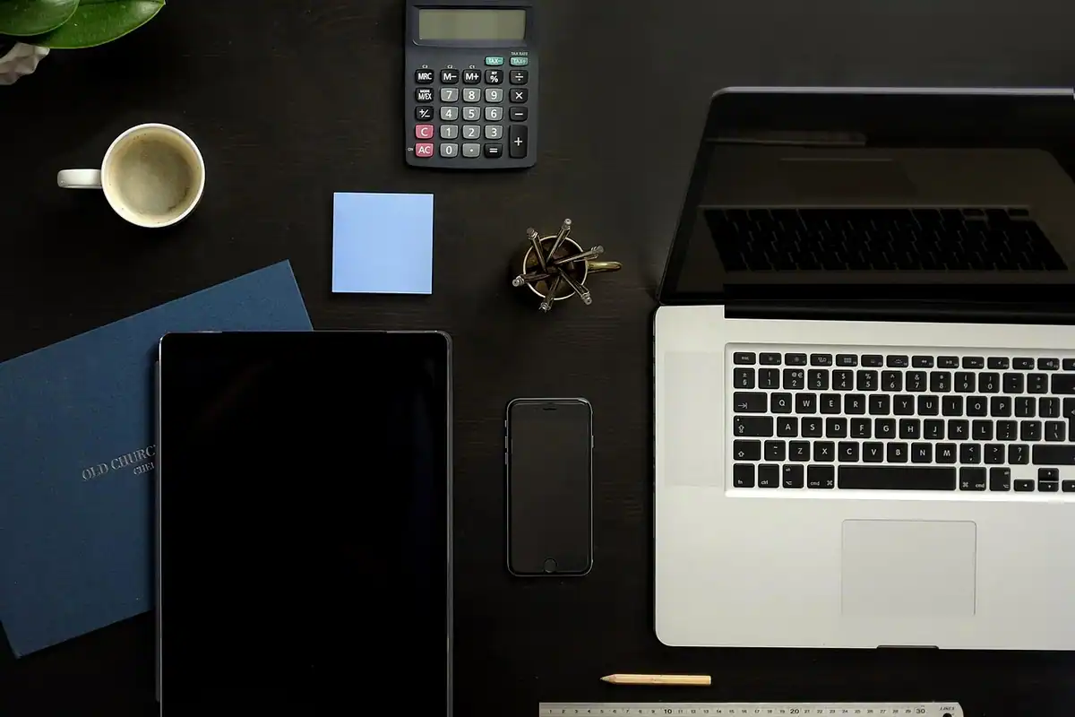 Birou cu laptop, calculator, agendă și telefon negru, văzut de sus