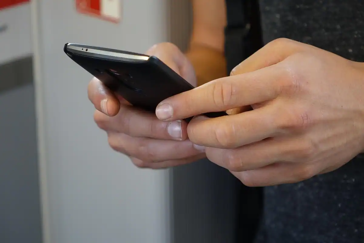 Mâini care țin un telefon negru în timpul unei utilizări îndelungate