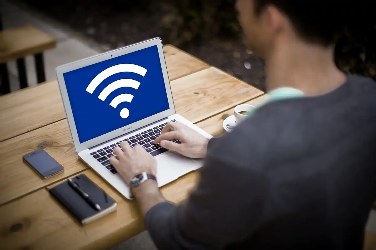 Bărbat la un laptop cu simbol Wi-Fi mare pe ecran