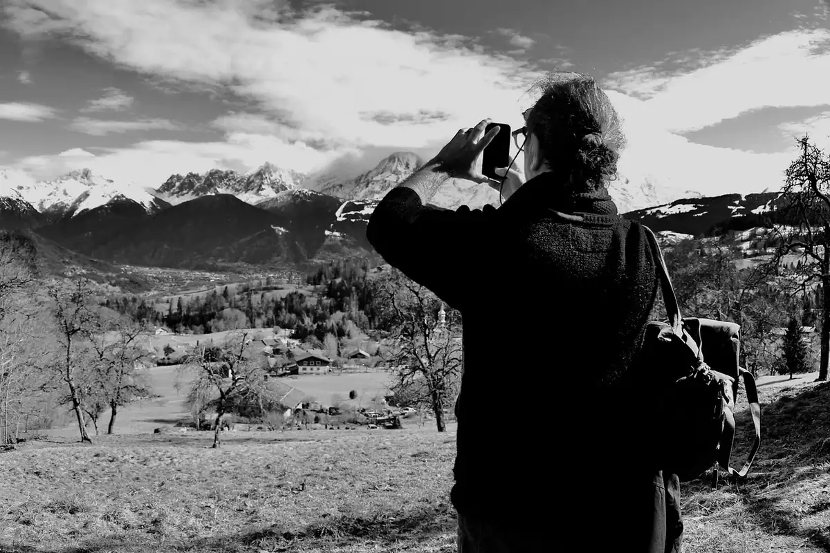 Fotograf în alb-negru care fotografiază un peisaj montan